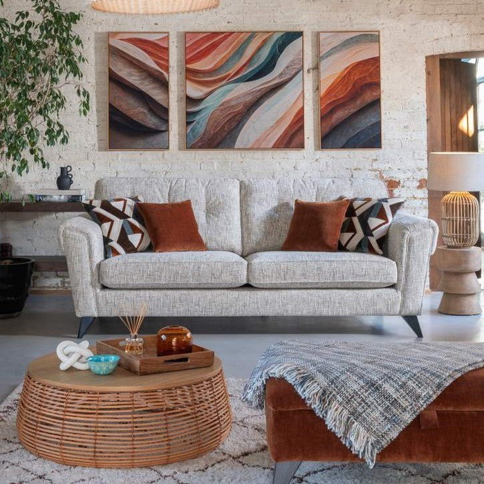 Living room with a grey sofa, patterned armchair, and wicker coffee table, with large conservatory style floor to ceiling window.